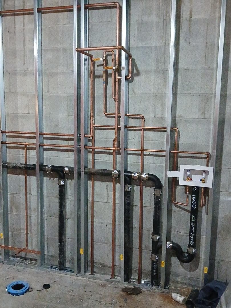 Copper supply lines and black drain piping roughed in for back-to-back bathrooms