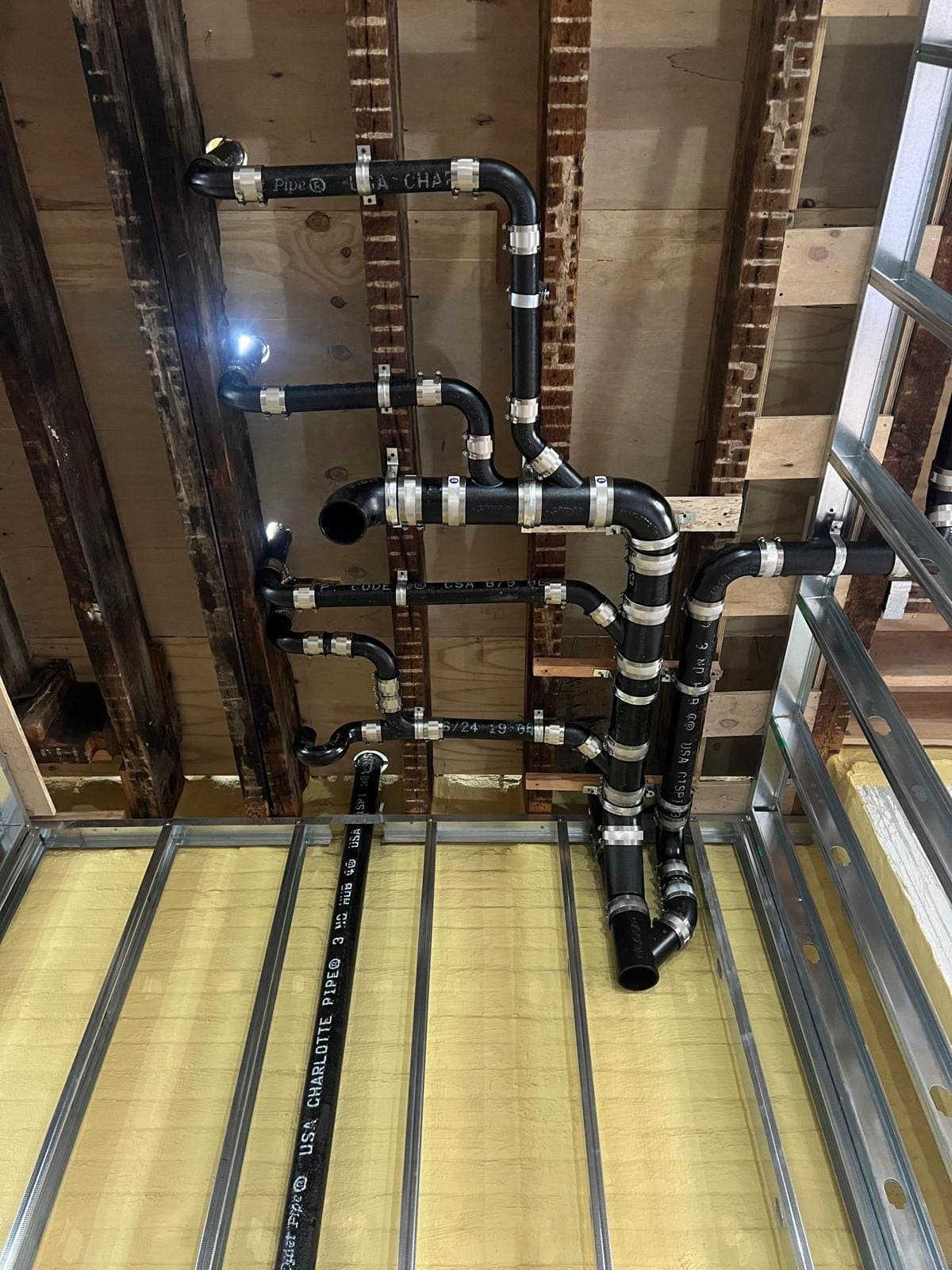 No-hub cast iron drain and vent piping between ceiling joists during a renovation