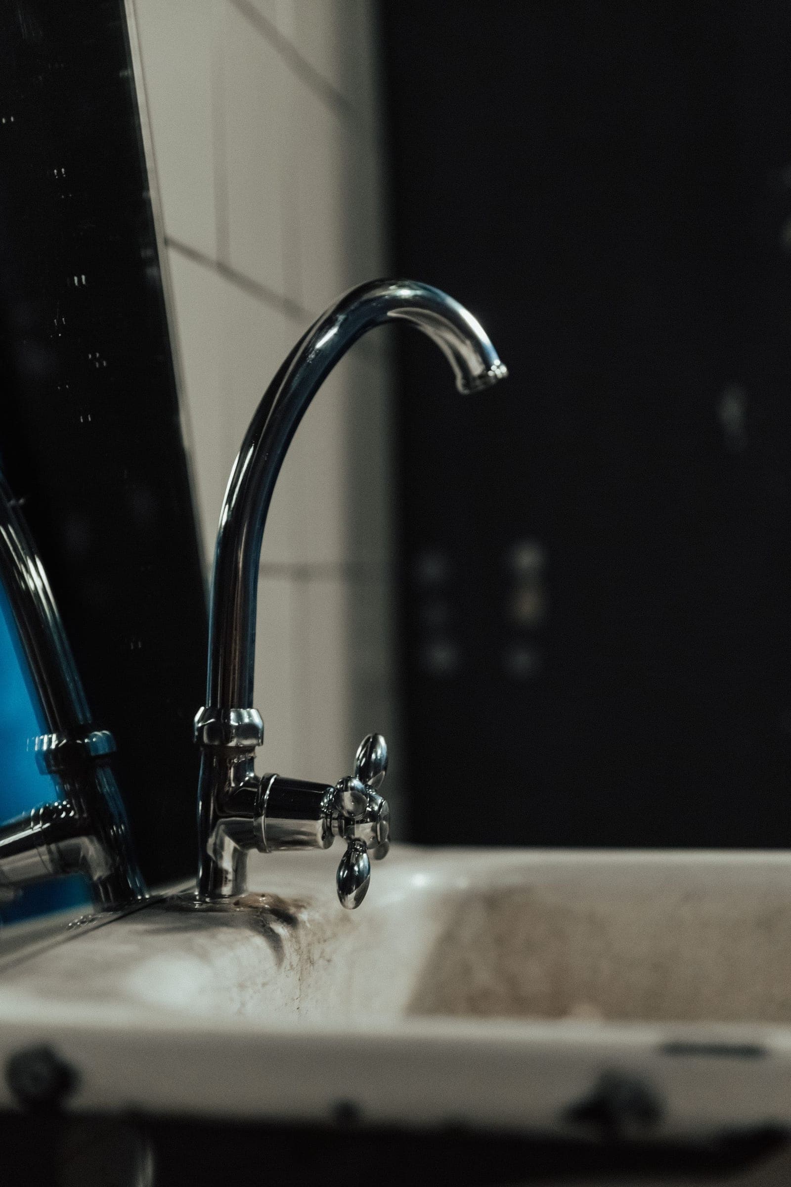 Chrome faucet over an old sink in low light