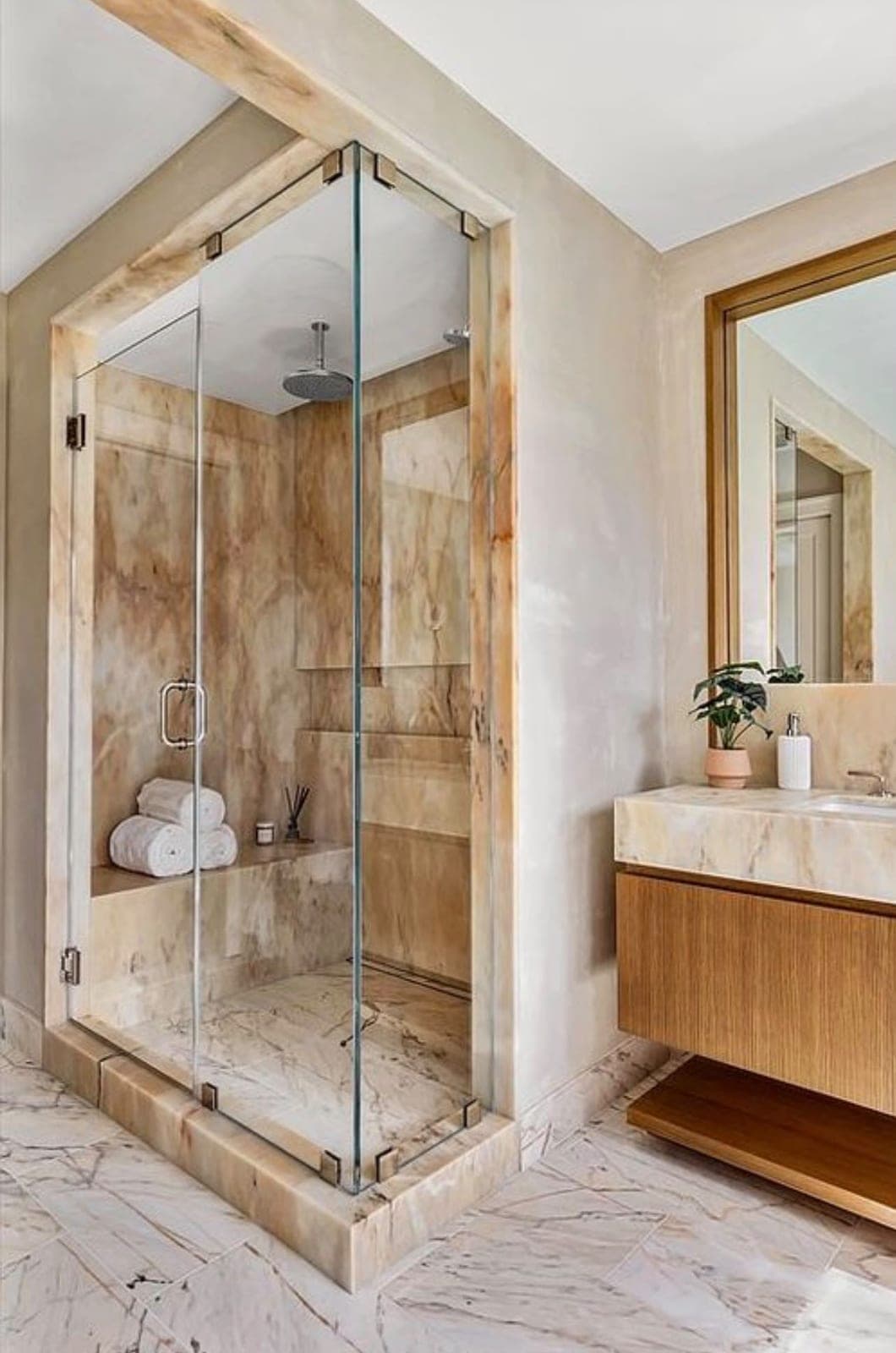 Finished stone walk-in shower with a frameless glass enclosure