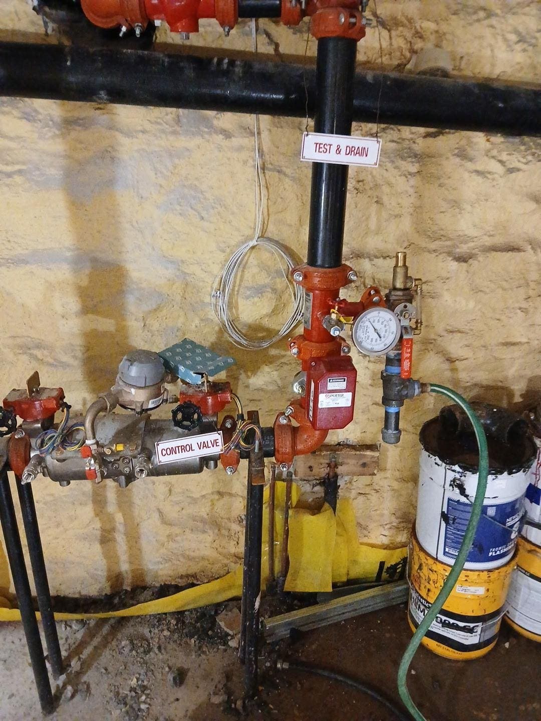 Sprinkler control valve, test and drain assembly and pressure gauge in a building basement