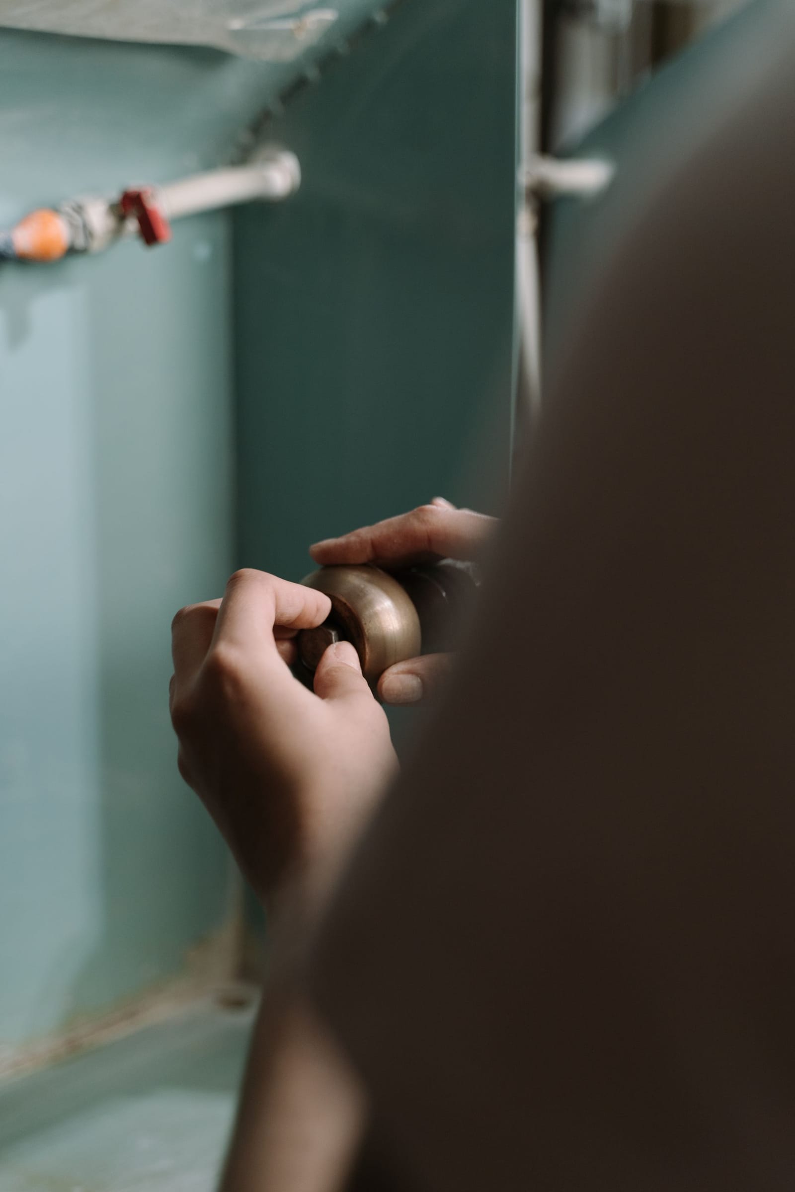 Hands adjusting a pipe connection underneath a sink