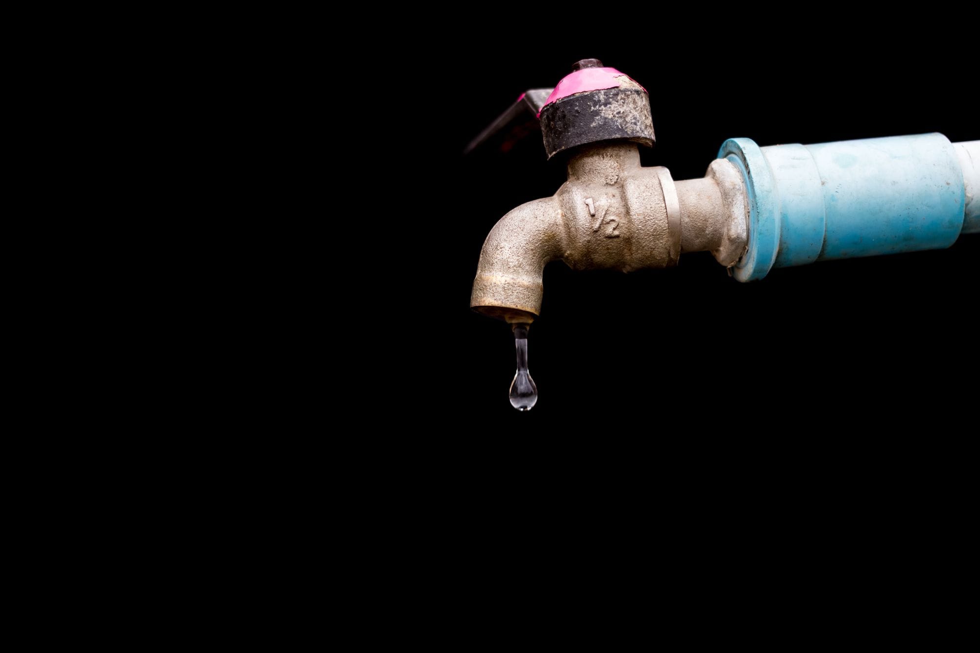 Water drop falling from a dripping brass tap