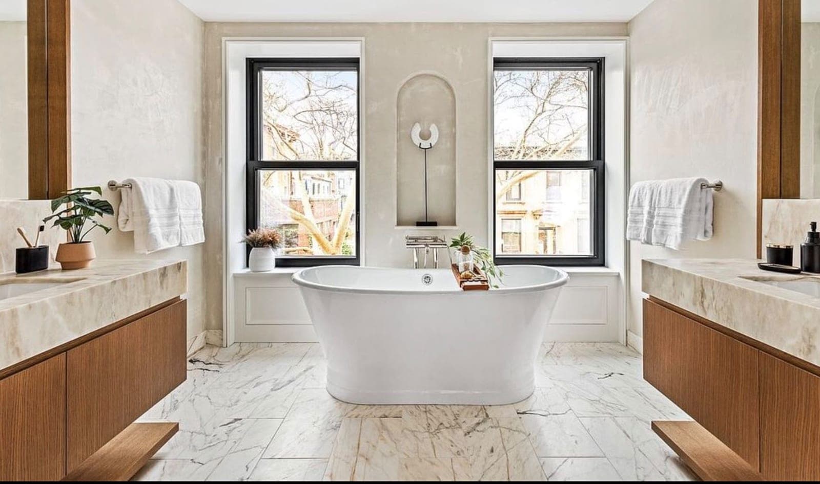 Finished primary bathroom with a freestanding tub between two vanities