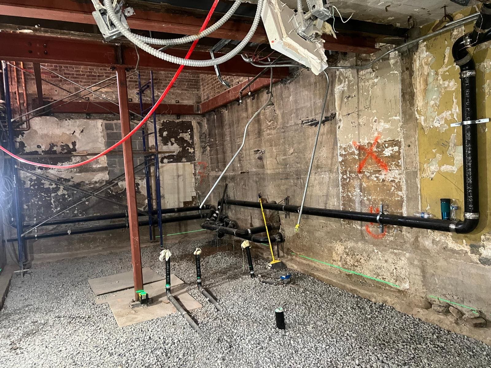 Underground drain piping roughed in on gravel in a basement before the concrete slab is poured